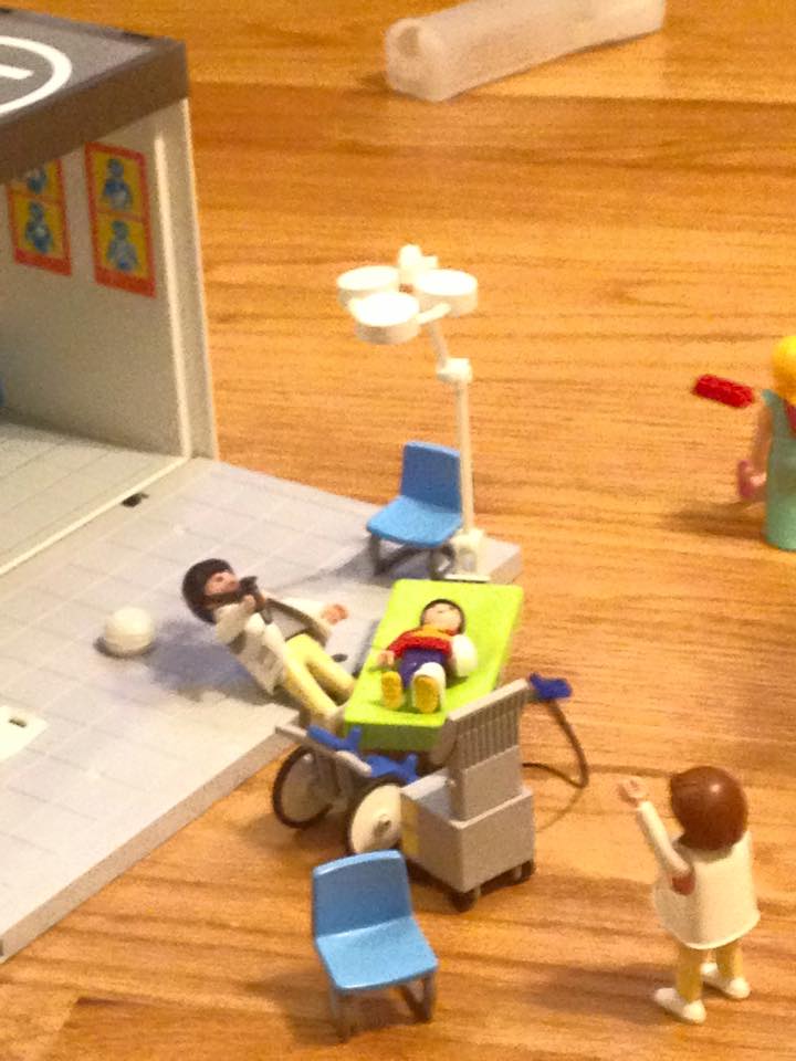 Image showing doctor play with toys. Patient is laying on the table and is being cared for by doctors.